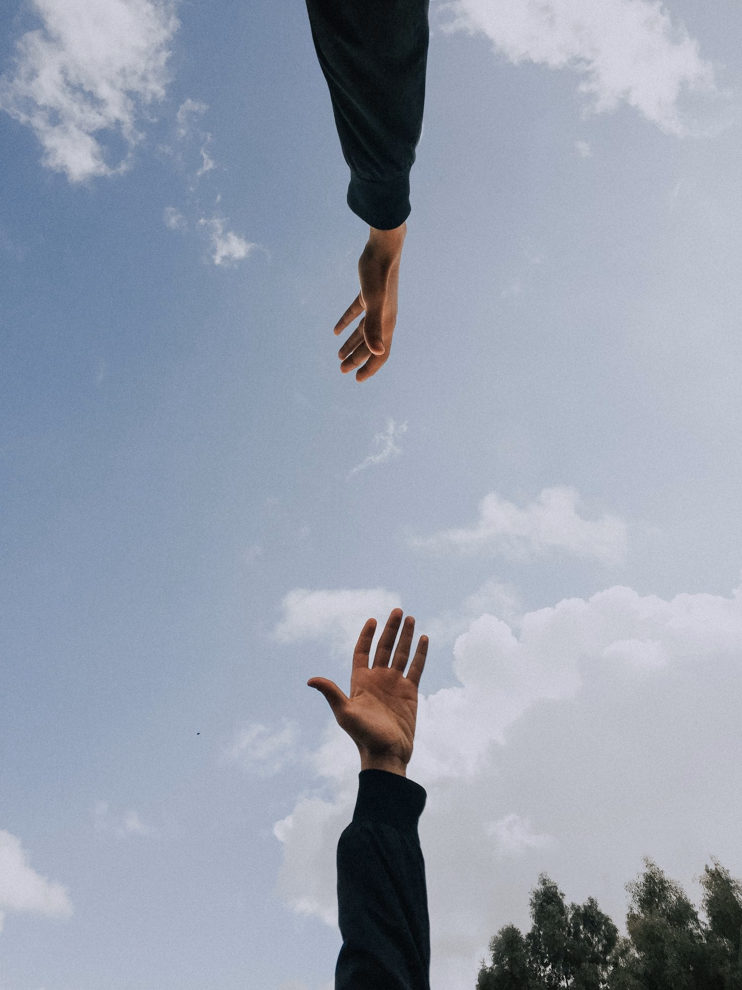 Dos manos que se alcanzan contra un cielo despejado